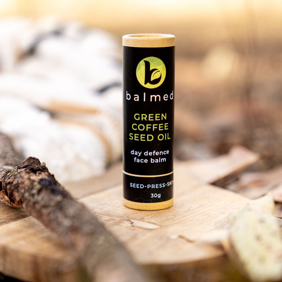 Green Coffee seed oil Face balm stick sitting on piece of wood