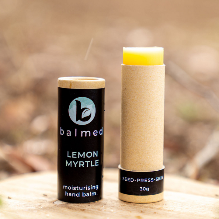 Hand Balm Stick with lid off sitting on a wooden table